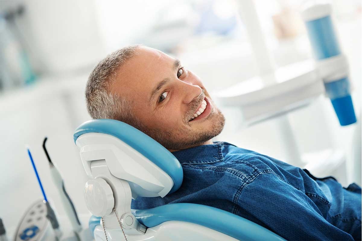 man smiling comfortably in dental chair before receiving a custom dental crown at Stillwater Dental Associates in Bangor, ME